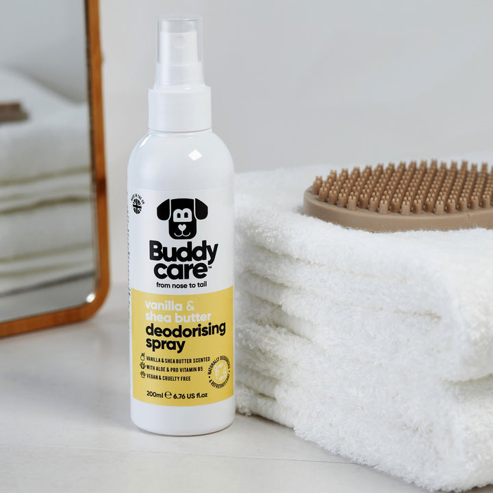 Buddycare Vanilla and Shea Butter Dog Deodorising Spray beside towels and a grooming brush